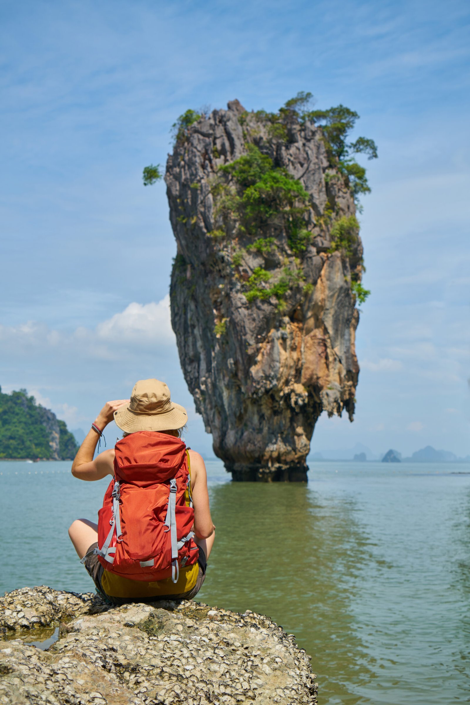 backpacker girl sitting on a rock at james bond island, thailand